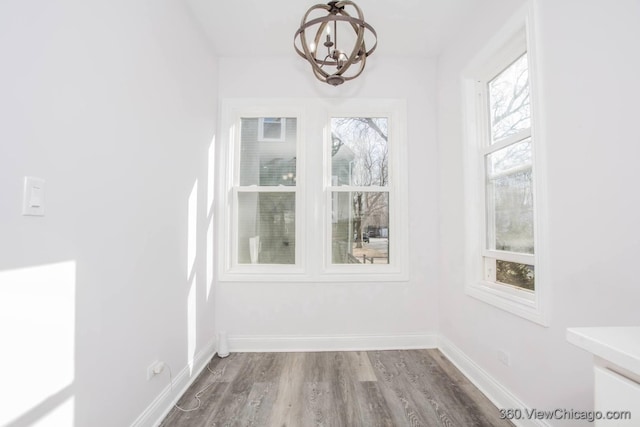 unfurnished dining area with an inviting chandelier and wood-type flooring