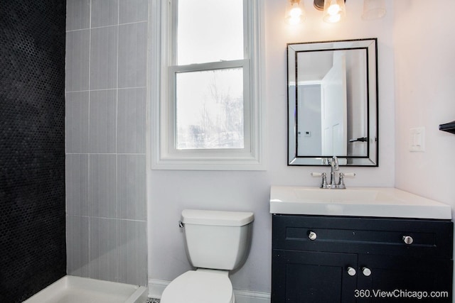 bathroom with tiled shower, vanity, and toilet