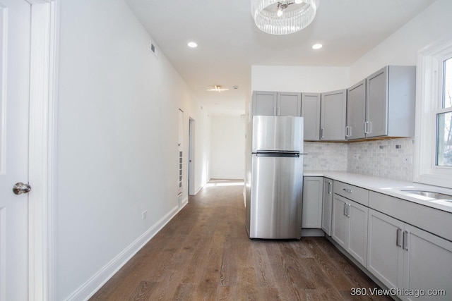 kitchen with tasteful backsplash, stainless steel fridge, dark hardwood / wood-style flooring, and gray cabinetry