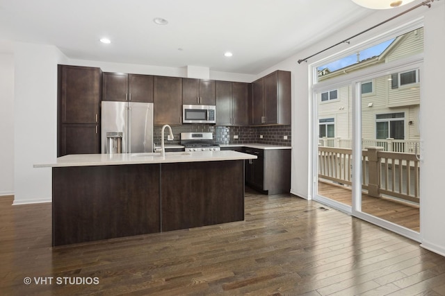 kitchen featuring tasteful backsplash, stainless steel appliances, dark hardwood / wood-style flooring, and an island with sink