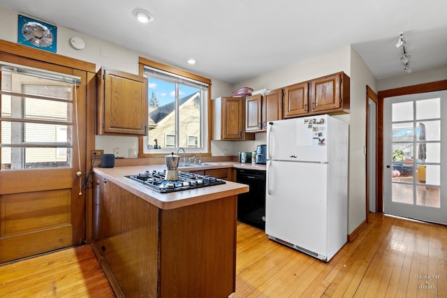 kitchen with black dishwasher, white fridge, stainless steel gas cooktop, light hardwood / wood-style floors, and kitchen peninsula