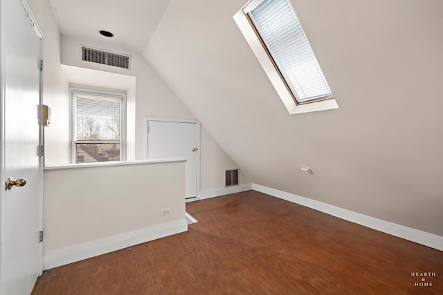 bonus room featuring dark wood-type flooring, a healthy amount of sunlight, and lofted ceiling with skylight