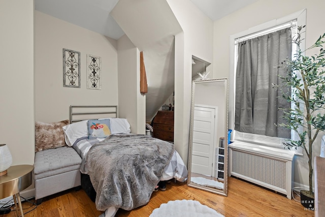 bedroom with radiator heating unit and wood-type flooring