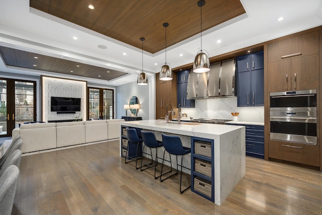 kitchen with double oven, a sink, wood ceiling, french doors, and a raised ceiling