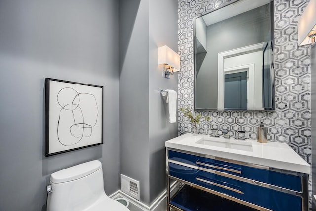 bathroom featuring backsplash, visible vents, vanity, and toilet