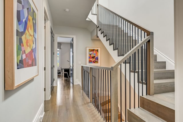 hallway with stairway, wood finished floors, and baseboards