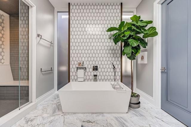 full bathroom featuring marble finish floor, a freestanding tub, and baseboards