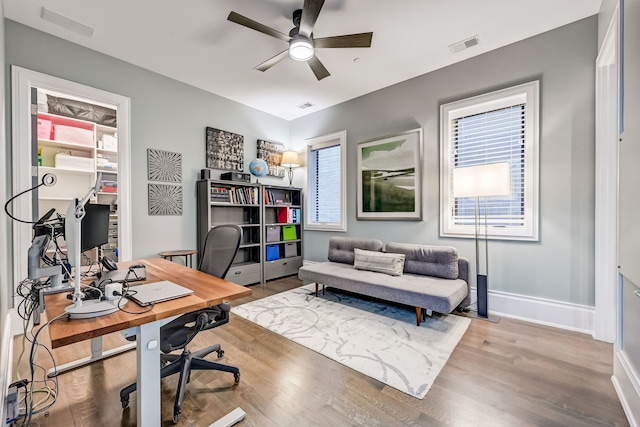 office with a ceiling fan, visible vents, baseboards, and wood finished floors