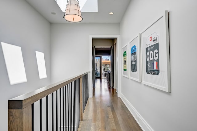 hall featuring a skylight, recessed lighting, baseboards, and wood finished floors