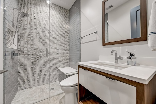 bathroom with toilet, a stall shower, vanity, and visible vents