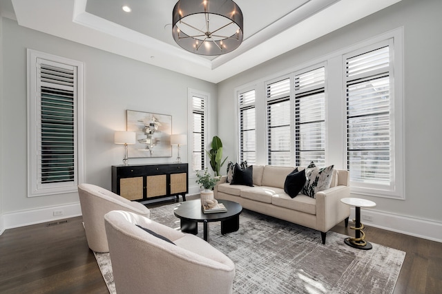 living room featuring an inviting chandelier, baseboards, a raised ceiling, and wood finished floors