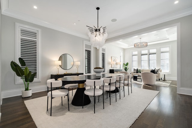 dining room featuring a raised ceiling, an inviting chandelier, ornamental molding, dark wood-type flooring, and baseboards