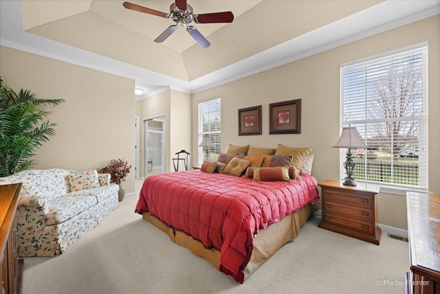 bedroom with a tray ceiling, a ceiling fan, ornamental molding, visible vents, and light carpet