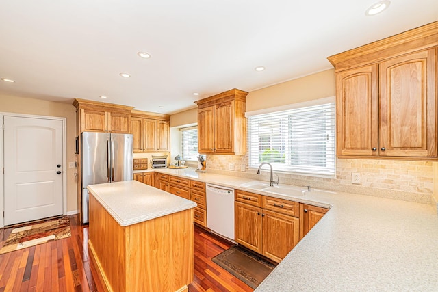 kitchen featuring a center island, light countertops, freestanding refrigerator, white dishwasher, and a sink