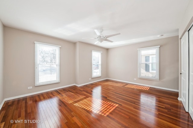 unfurnished room featuring dark wood-style flooring, a ceiling fan, and baseboards