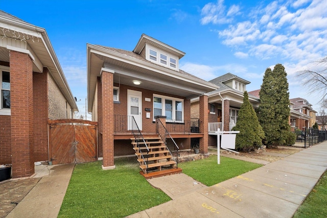 bungalow-style home featuring a porch, a front lawn, fence, and brick siding