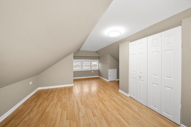 bonus room with vaulted ceiling, light wood-style flooring, and baseboards