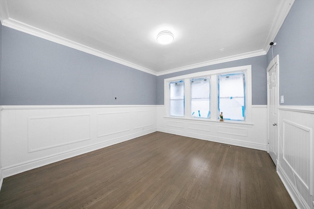 spare room featuring a wainscoted wall, dark wood-type flooring, ornamental molding, and visible vents