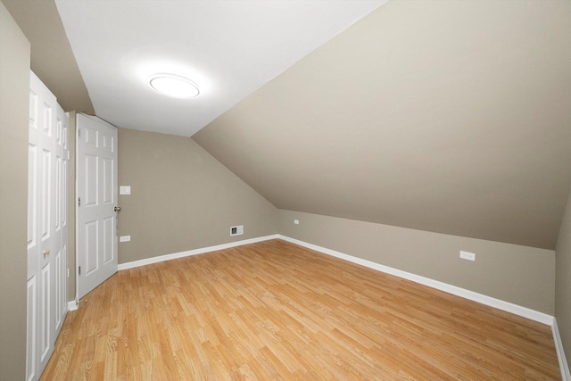 bonus room with light wood-type flooring, visible vents, baseboards, and vaulted ceiling