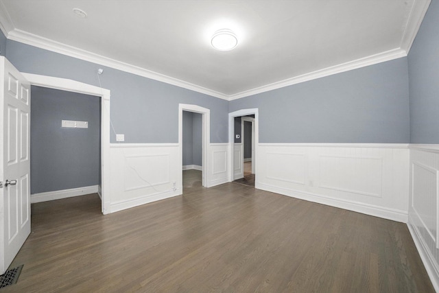 spare room with wainscoting, dark wood finished floors, visible vents, and crown molding