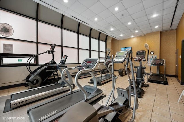 workout area with a paneled ceiling and light tile patterned floors