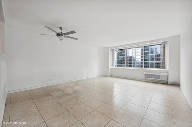 tiled empty room featuring an AC wall unit and ceiling fan