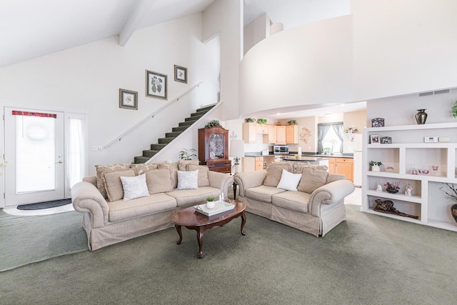 carpeted living room with high vaulted ceiling and beamed ceiling