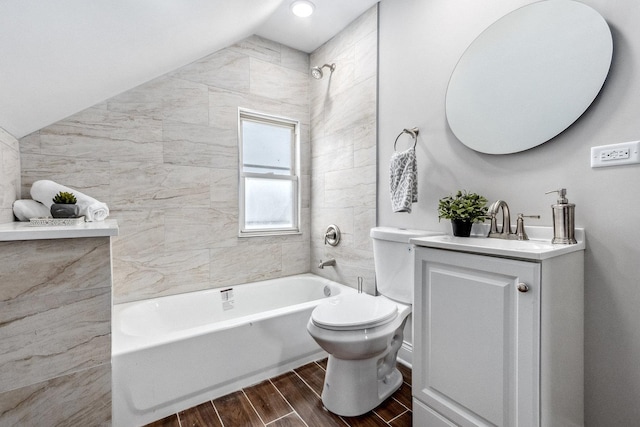 full bathroom with tiled shower / bath, lofted ceiling, vanity, and toilet