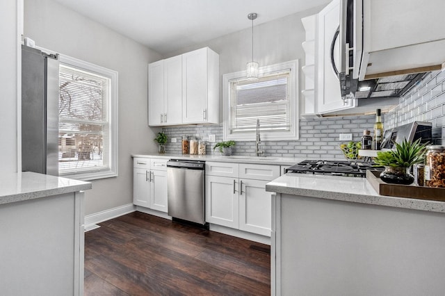 kitchen featuring white cabinetry, hanging light fixtures, stainless steel appliances, and light stone countertops