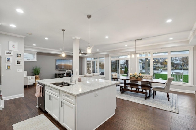 kitchen featuring decorative light fixtures, a kitchen island with sink, sink, and white cabinets