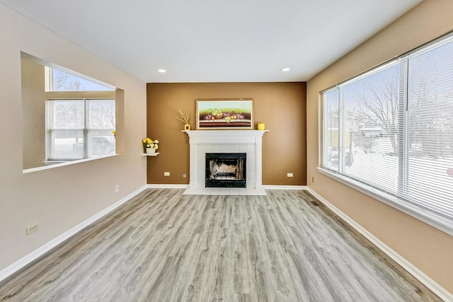 unfurnished living room with recessed lighting, baseboards, a tiled fireplace, and wood finished floors