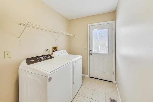 washroom featuring light tile patterned floors, laundry area, visible vents, baseboards, and washer and dryer