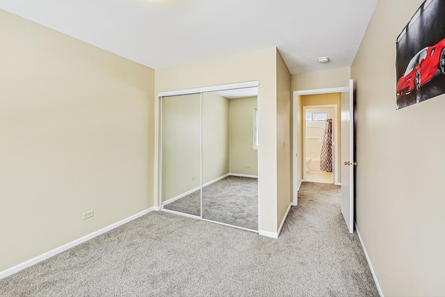 unfurnished bedroom featuring carpet, a closet, and baseboards