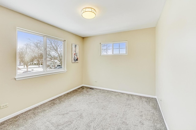 carpeted spare room with visible vents and baseboards