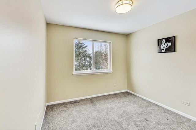 empty room with carpet, visible vents, and baseboards