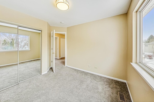 unfurnished bedroom featuring carpet, a closet, visible vents, and baseboards