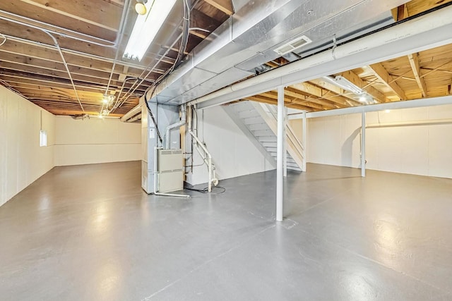 unfinished basement with heating unit, stairs, and visible vents