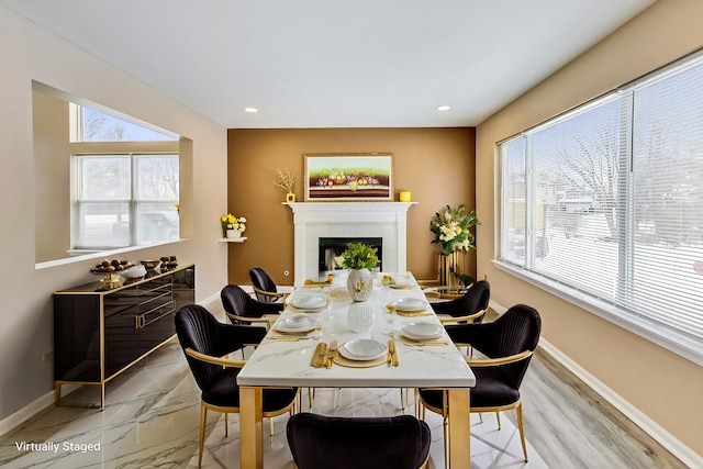 dining area with a tile fireplace, a healthy amount of sunlight, and baseboards