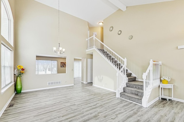 interior space featuring baseboards, visible vents, wood finished floors, beamed ceiling, and a chandelier