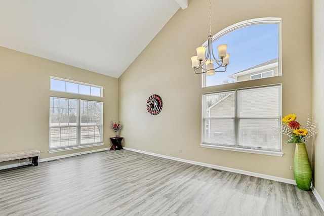 spare room featuring high vaulted ceiling, baseboards, and wood finished floors