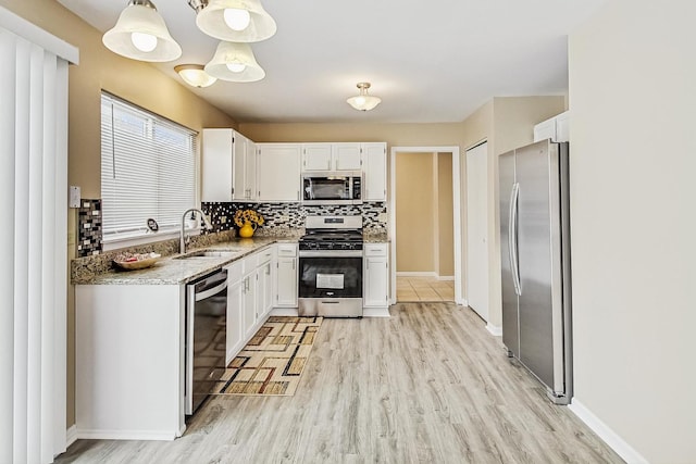 kitchen with tasteful backsplash, light stone counters, stainless steel appliances, light wood-type flooring, and a sink