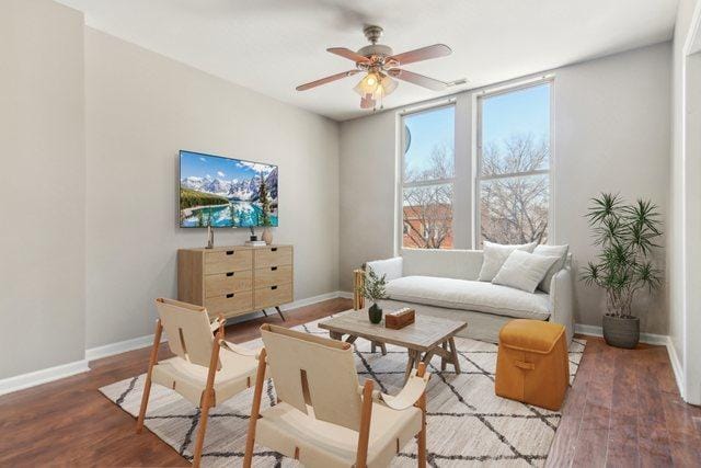 living room with baseboards, dark wood finished floors, and a ceiling fan