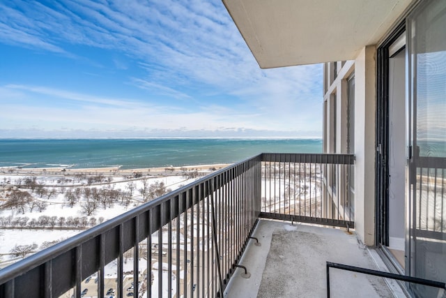 snow covered back of property with a water view