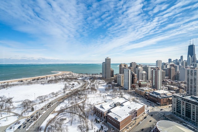 snowy aerial view featuring a view of city, a water view, and a view of the beach