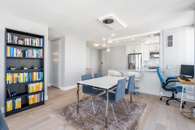 dining area with visible vents, light wood-style flooring, and baseboards