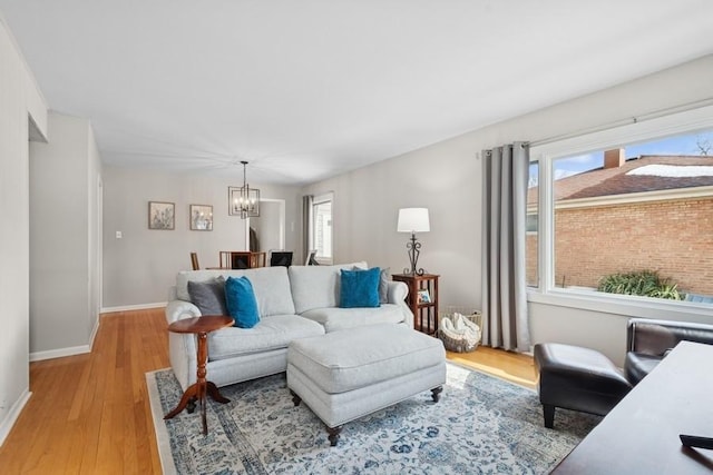 living room with baseboards, light wood finished floors, and a notable chandelier