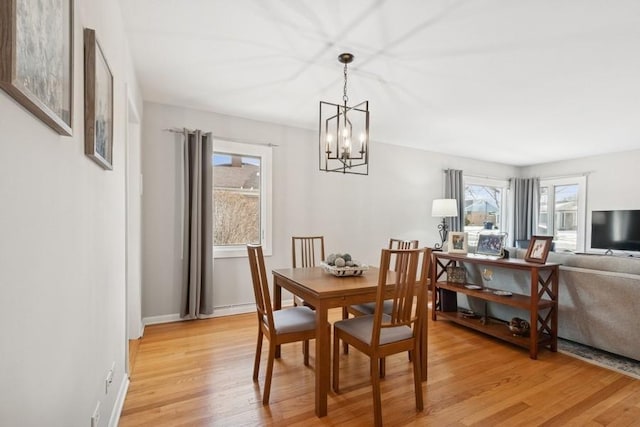 dining space with light wood-style floors, baseboards, and a chandelier