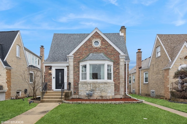 view of front of house featuring brick siding, a front yard, and a shingled roof