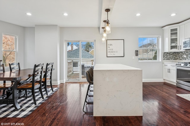 kitchen featuring glass insert cabinets, stainless steel range, dark wood finished floors, and decorative backsplash