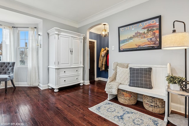 sitting room featuring baseboards, crown molding, arched walkways, and wood finished floors